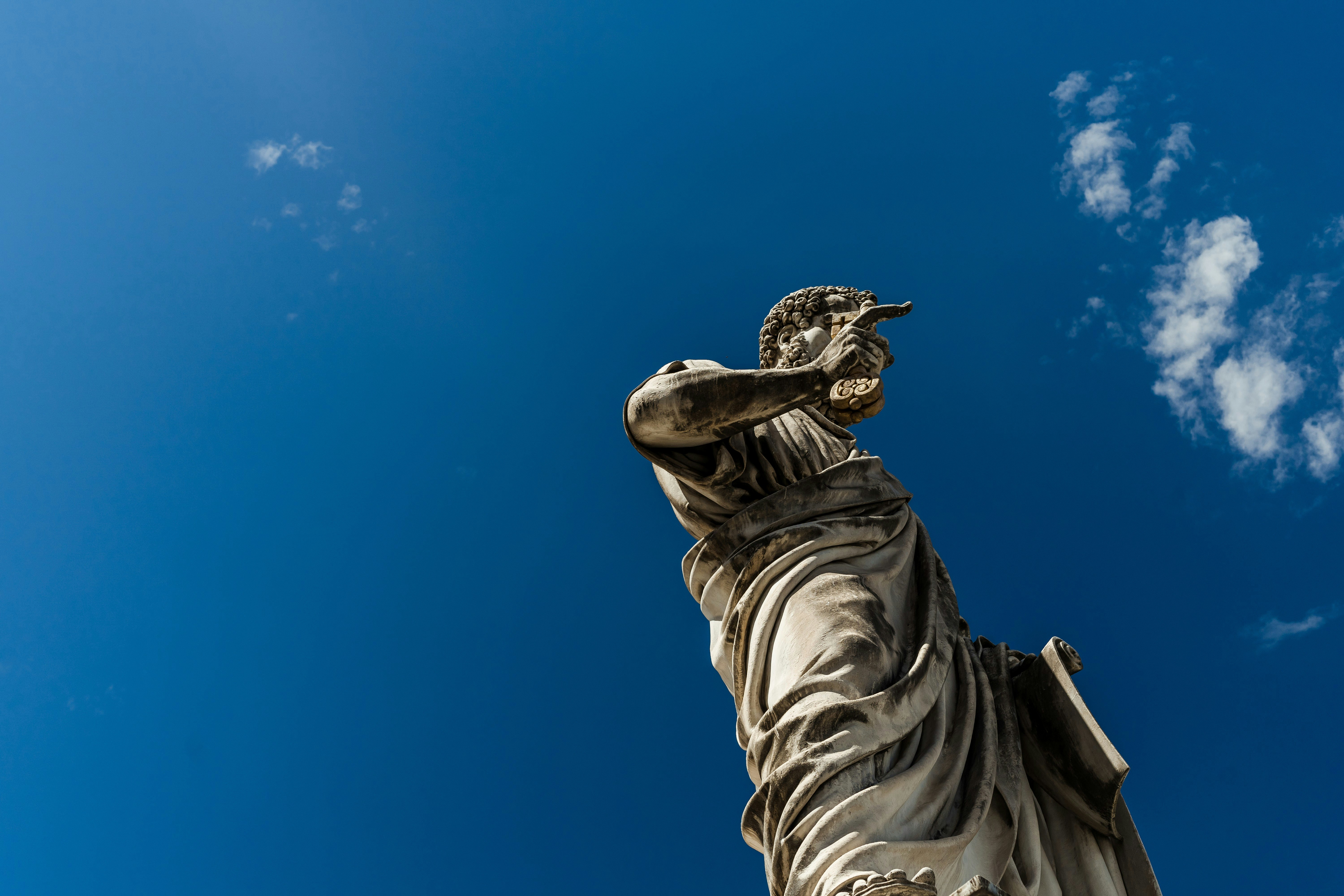 man standing statue under blue and white skies